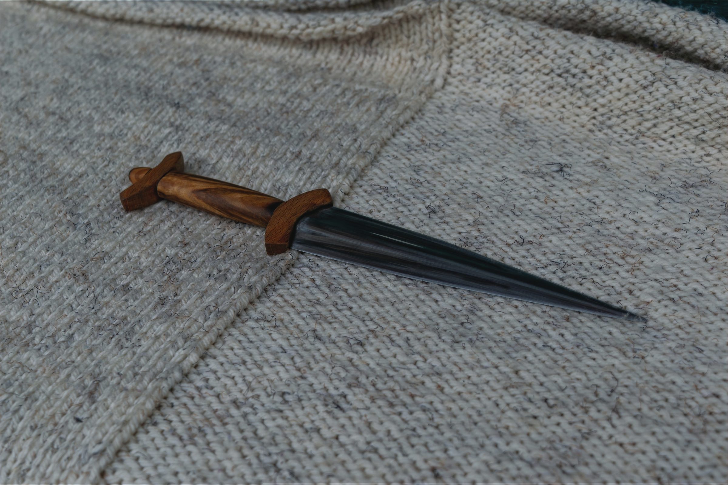 Bouranton dagger – miniature reproduction with carbon steel blade and olive wood grip, resting on pale wool